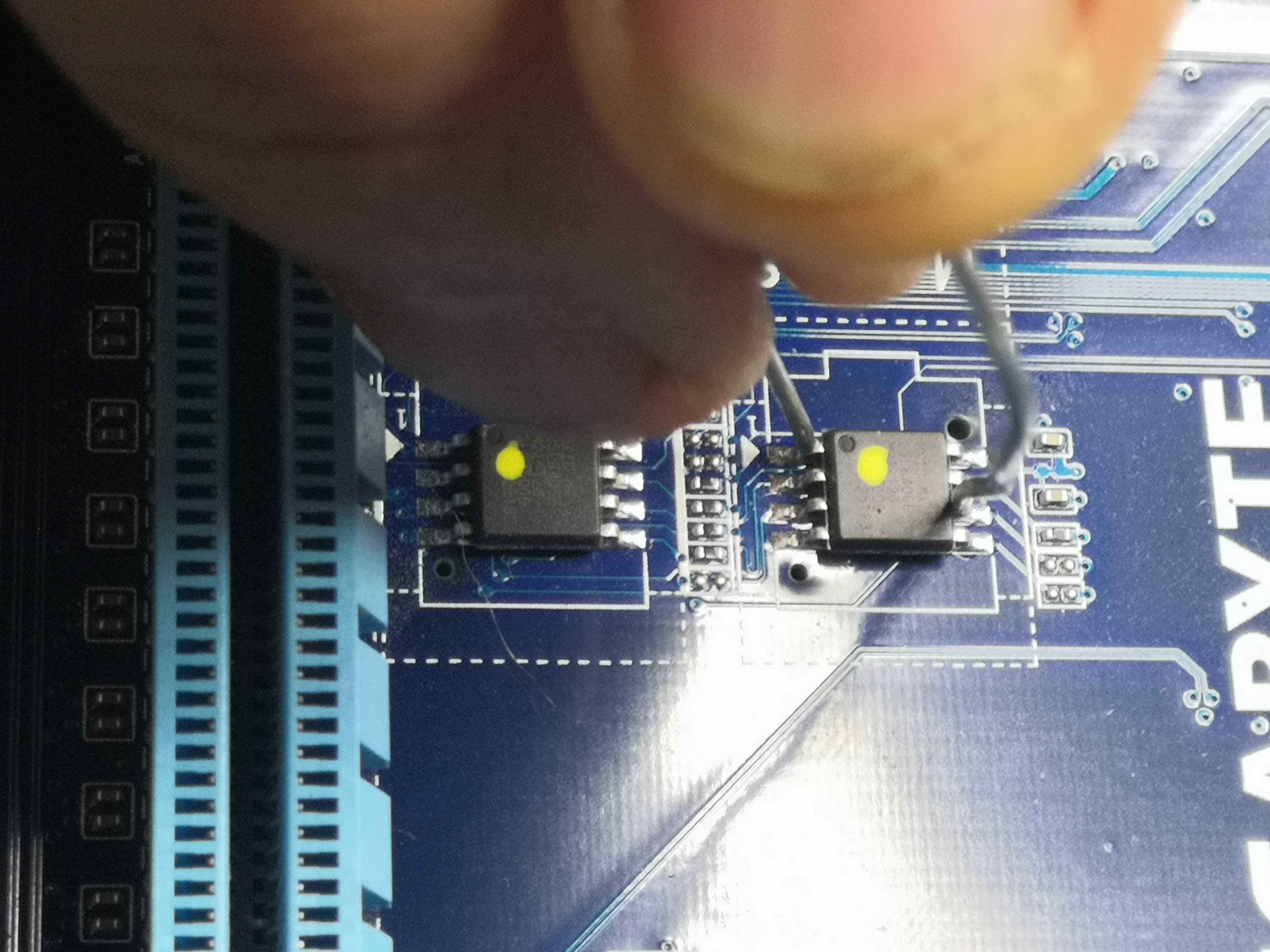 Les deux chips BIOS en gros plan — le fil de shunt est visible entre les pattes du M_BIOS à droite